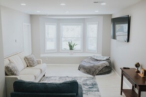 Un dormitorio moderno con una ventana grande, un sofá, una cama, un escritorio y un globo terráqueo.