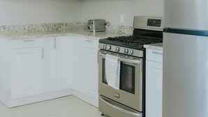A kitchen with white cabinets, a stainless steel refrigerator, a gas stove, and a toaster. - Modern 2BR • Gated Parking • 10 Min to Downtown (Detroit)