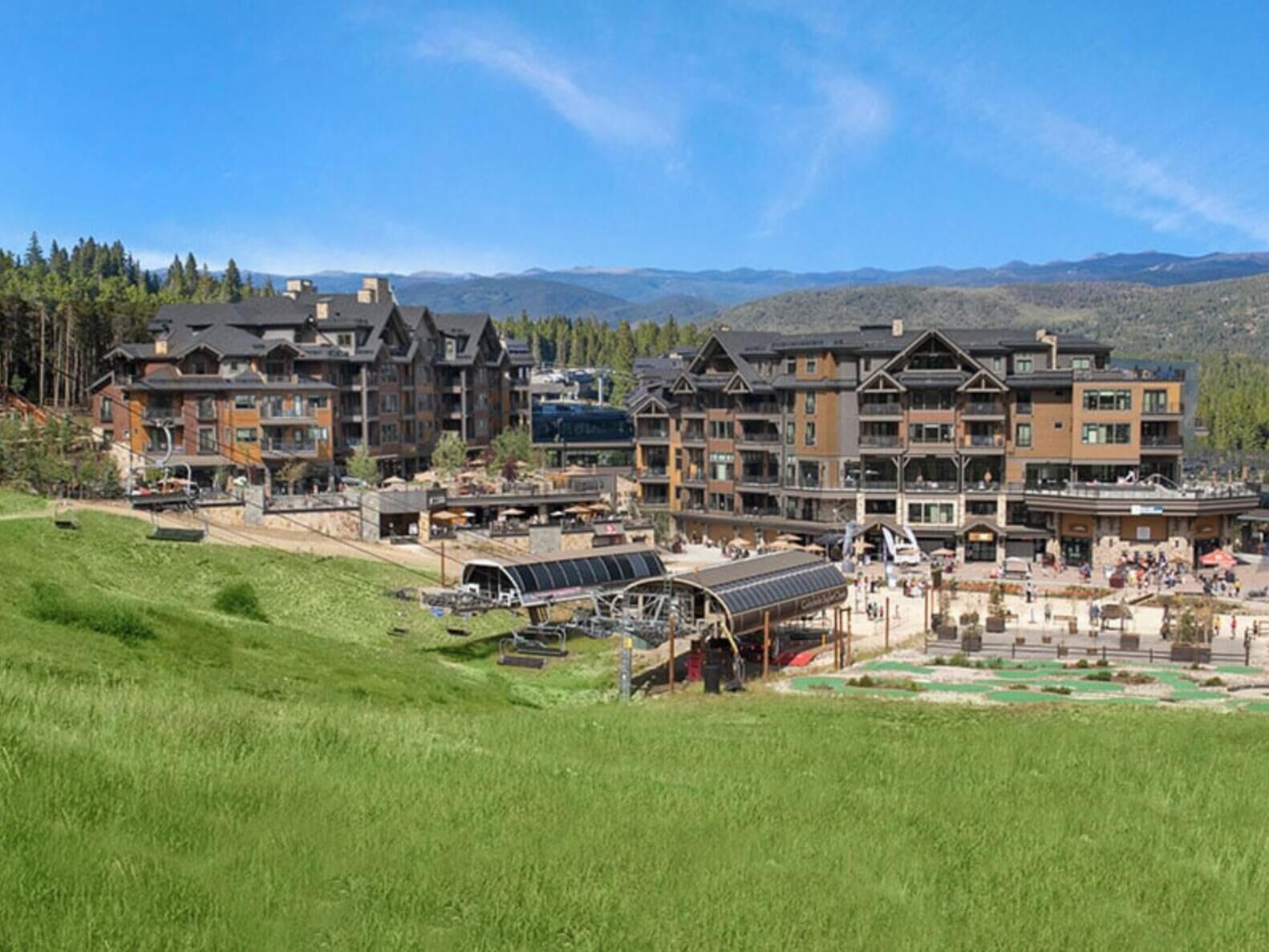 A multi-story hotel with a ski lift and a ski slope in the foreground.