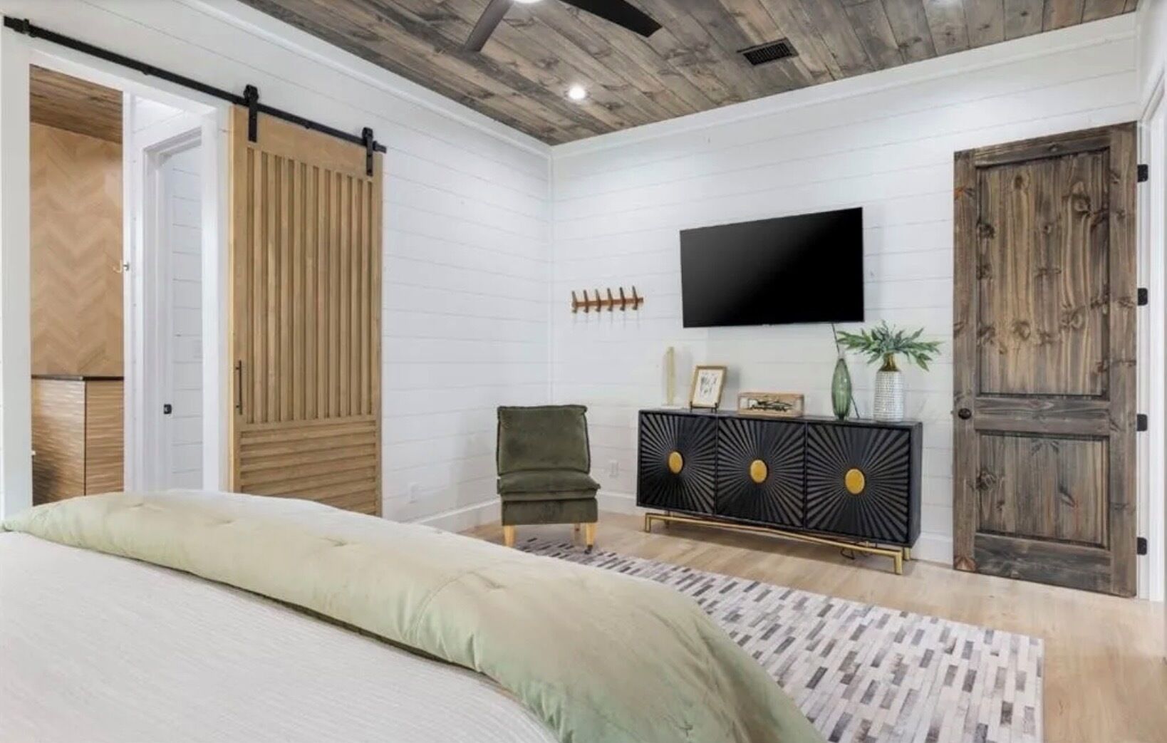 Un dormitorio con cama, puerta corredera, televisor, armario y otra puerta.