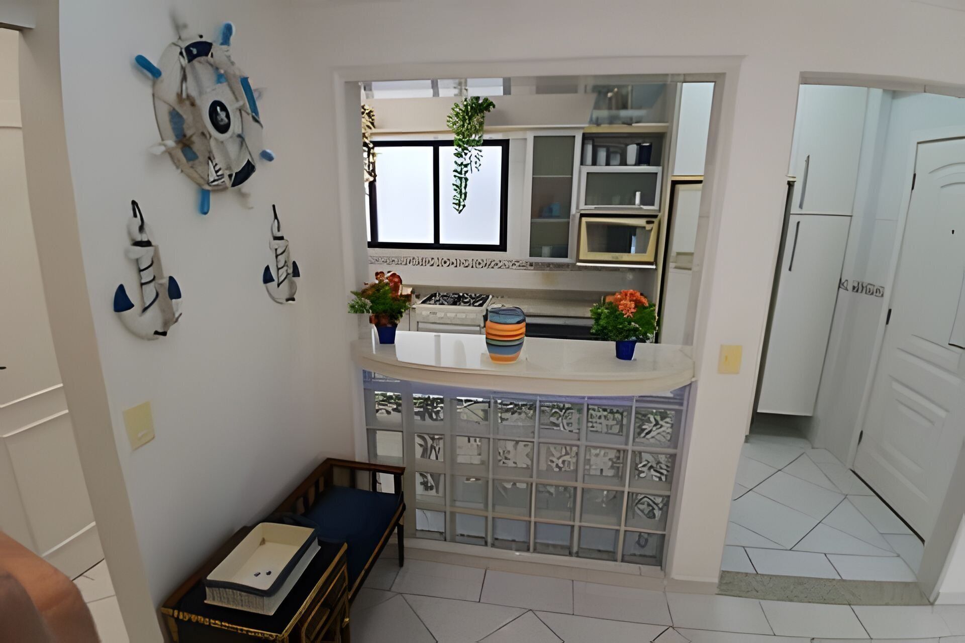 Cocina compacta con refrigerador integrado, una pequeña zona de comedor con banco y elementos decorativos en las paredes.