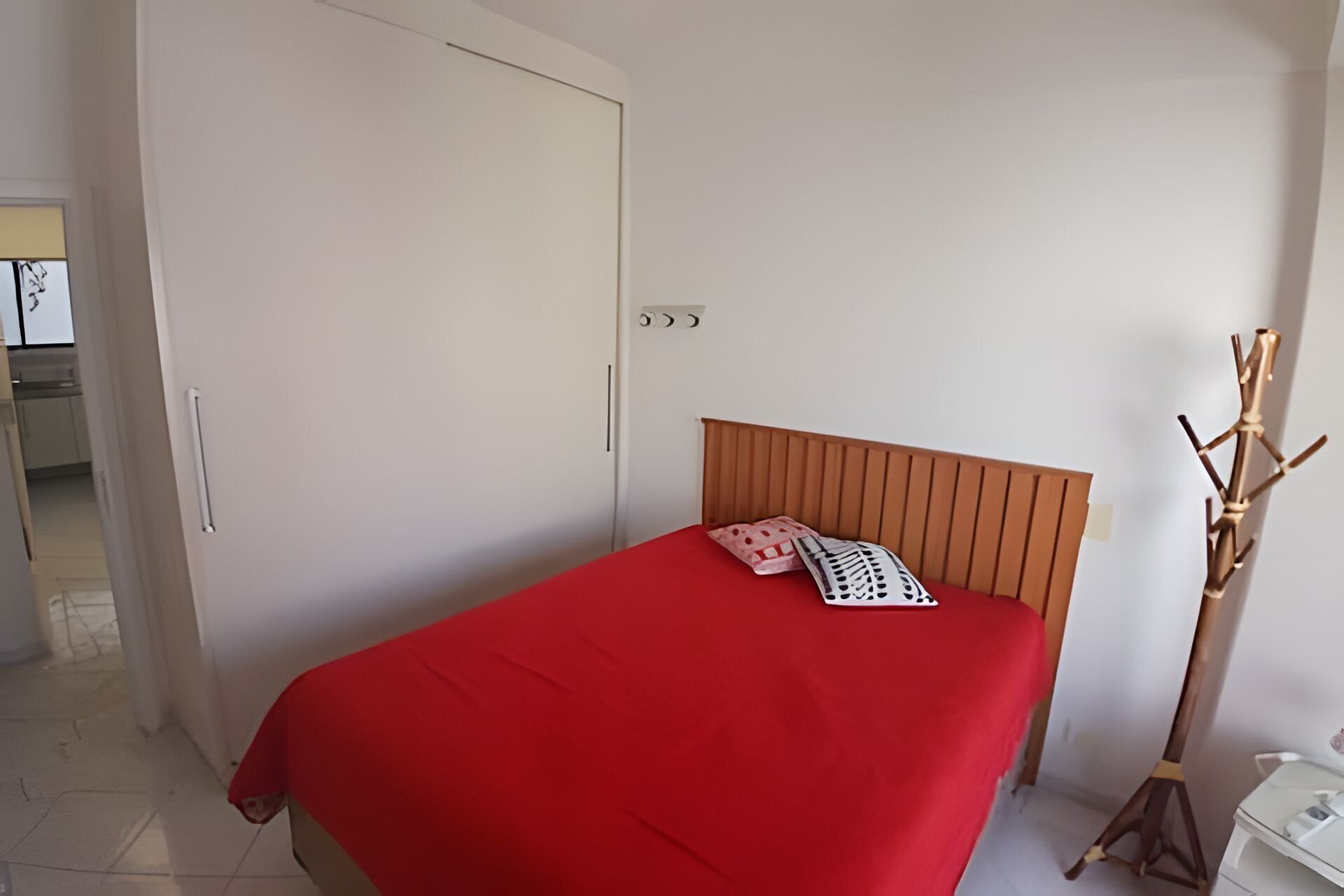 A bedroom with a bed, a wardrobe, and a nightstand.