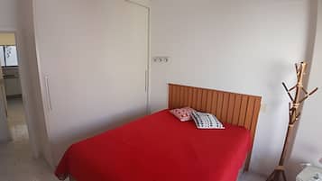 Un dormitorio con cama, armario y mesita de noche.