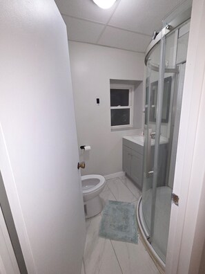 Ein Badezimmer mit Toilette, Dusche und einem Fenster.