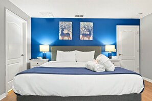 A hotel room with a large bed, two bedside tables with lamps, and two wall art pieces. - Free Pool Heat | Hypoallergenic Private Villa | Lux Resort (Four Corners)