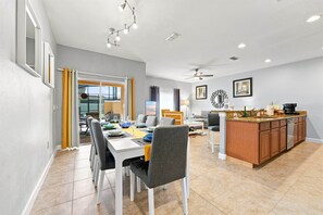 A modern kitchen with a central island, dining area with chairs and table, and a view to the outside. - Free Pool Heat | Hypoallergenic Private Villa | Lux Resort (Four Corners)