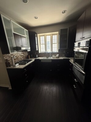 A modern kitchen with dark cabinetry, a central island, and a window above the sink.