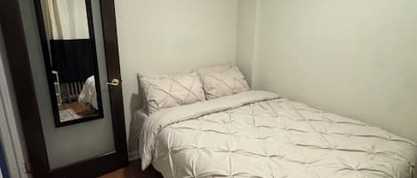 A bedroom with a bed, a rug, and a door with a mirror.