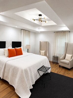 A modern hotel room with a large bed, a chair, a small table, and a ceiling light fixture. - 3BR House Near Mercedes Stadium Sleeps 8 w/ free Parking, A/C, Laundry, & Gazebo (Atlanta)