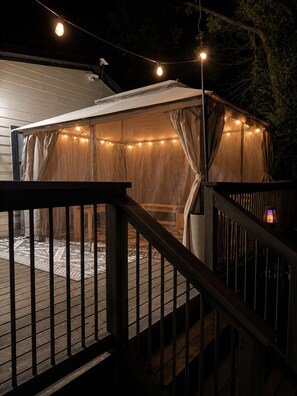 Ein überdachter Außenbereich mit Holzdeck, Lichterkette und einer Pergola.