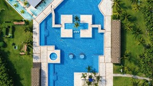 An aerial view of a resort with multiple swimming pools, palm trees, and a covered area. - Luxury Ocean View Penthouse + Resort Pool (Playa del Carmen)