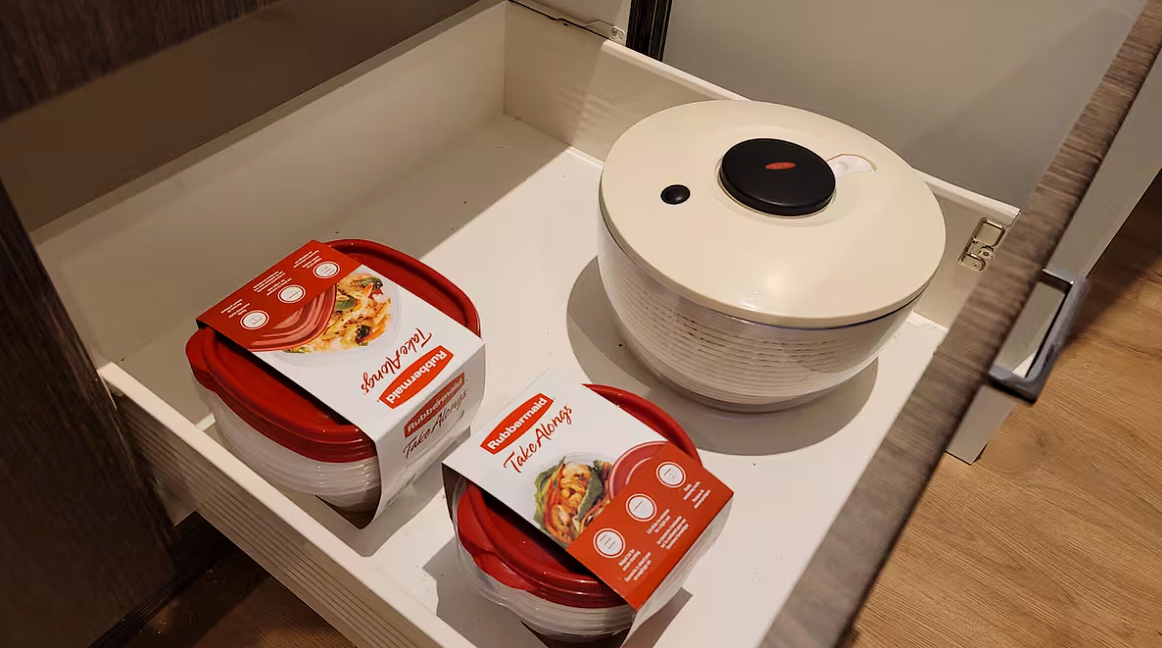 A kitchen drawer with two take-along containers and a stack of white plates.