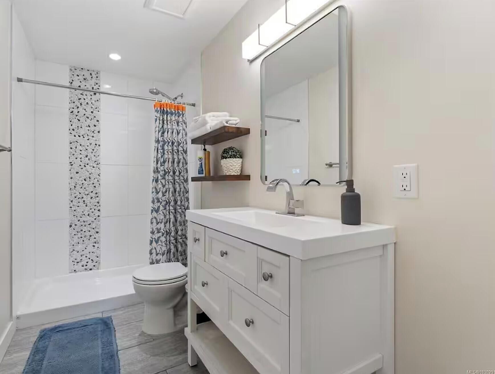 A modern bathroom with a shower, toilet, and vanity.