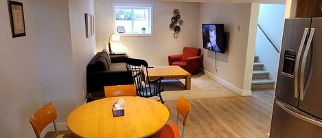 Un espacio habitable compacto con comedor, sofá, televisor y refrigerador.