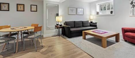 Una sala moderna con un sofá, una mesita de centro y una zona de comedor con sillas.