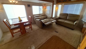 An RV interior with a dining table, two sofas, and a small rug.