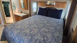 A bedroom with a bed, a vanity with a mirror, and a window.