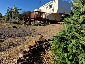 A recreational vehicle with a wooden deck and a white exterior. - Cozy One Bedroom Glamping Camper (Silver City)