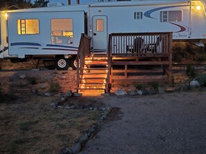 A recreational vehicle with a wooden deck and a ramp leading to the entrance.