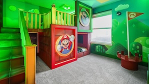 Um espaço infantil com uma cama temática do Mario, uma escada e paredes verdes.
