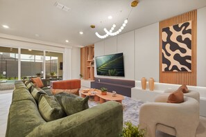 En moderne stue med et fladskærms-tv, sofaer, et sofabord og en dekorativ vægpanel.