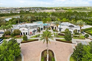 Un resort con piscina central, palmeras y un amplio estacionamiento.