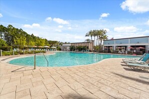 A swimming pool with lounge chairs and umbrellas, surrounded by a brick patio and palm trees. - 5 BD/ 4.5 BA/ The Enclaves at Festival (450 CD) (Davenport)