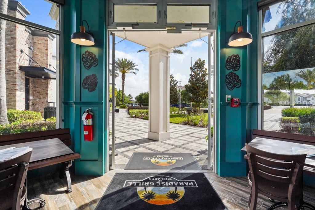 A hotel entrance with a teal color scheme, a fire extinguisher, and a doormat with a sun and palm tree design.
