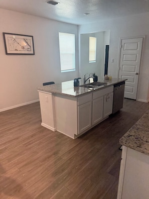 A kitchen with a central island, white cabinetry, and a door in the background. - Charming/ Modern  4-bedroom townhome in San Antonio (San Antonio)
