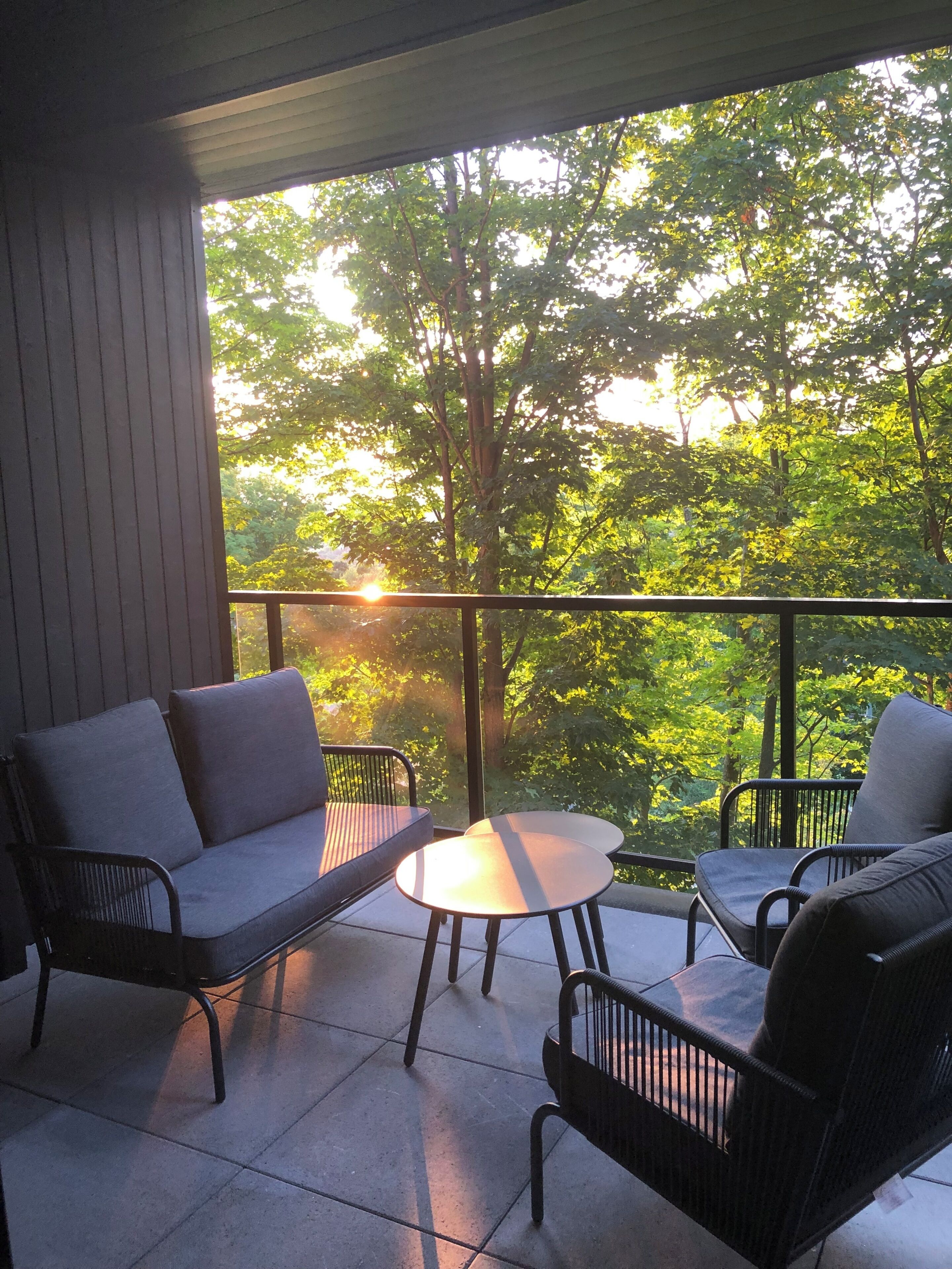 Een balkon met een bank, twee stoelen en een kleine tafel.