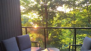 Ein Balkon mit einer Couch, zwei Stühlen und einem kleinen Tisch.