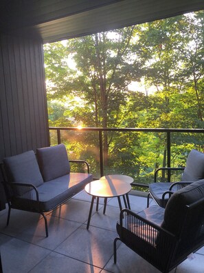 Ein Balkon mit einer Couch, zwei Stühlen und einem kleinen Tisch.