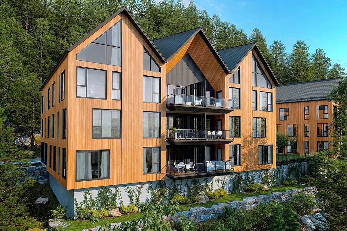 Una cabaña moderna de madera con varios niveles, ventanas amplias y un balcón.
