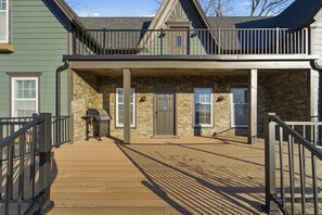 Un bâtiment à deux étages doté d’un porche couvert, d’un barbecue et d’une terrasse en bois.