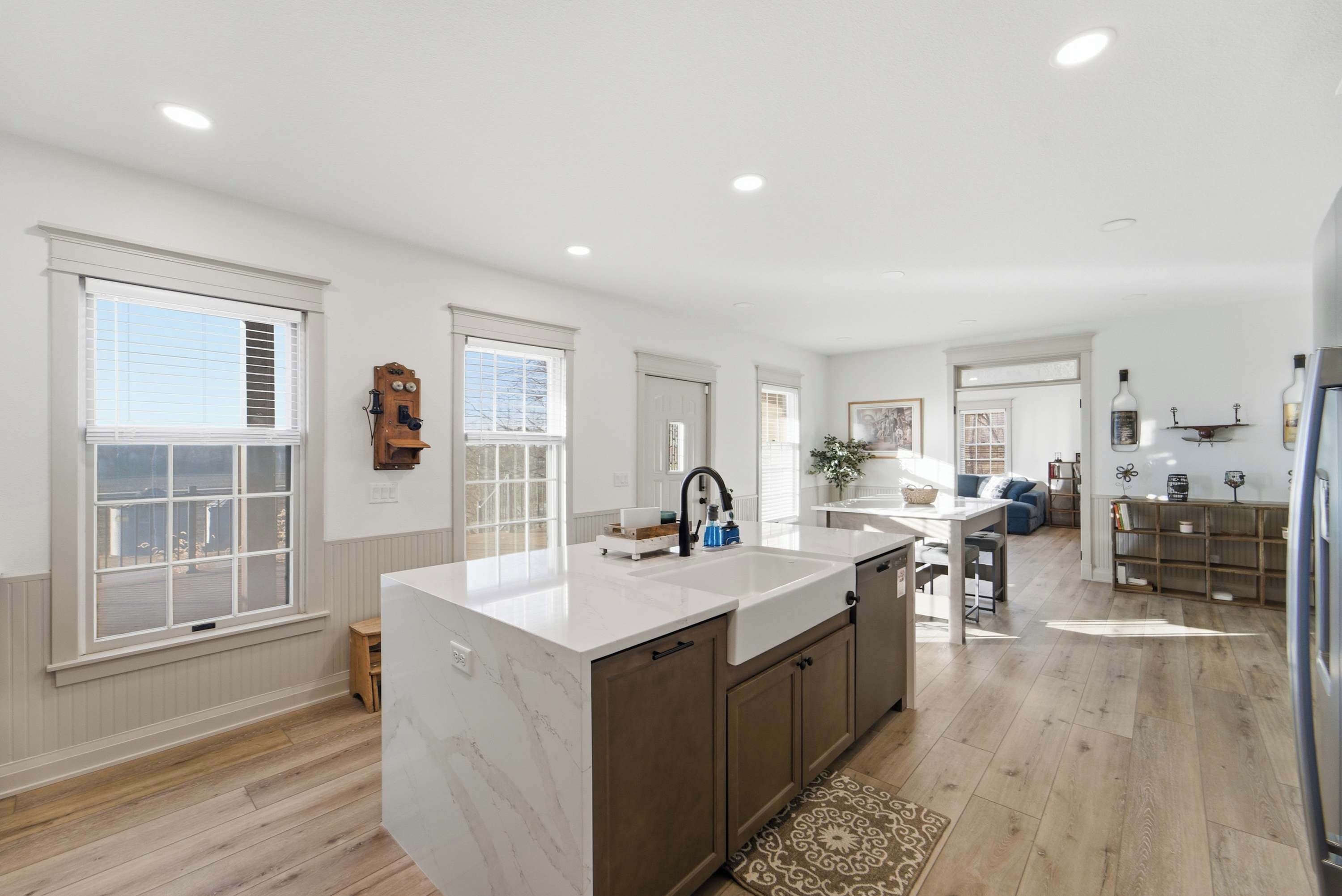 A spacious kitchen with a large island, wooden cabinets, and a view to the living area.