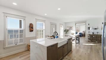 A spacious kitchen with a large island, wooden cabinets, and a view to the living area.