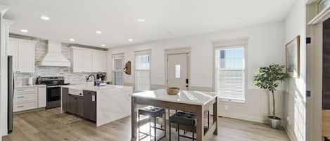 A modern kitchen with white cabinetry, a central island, and a dining area with a table and chairs.