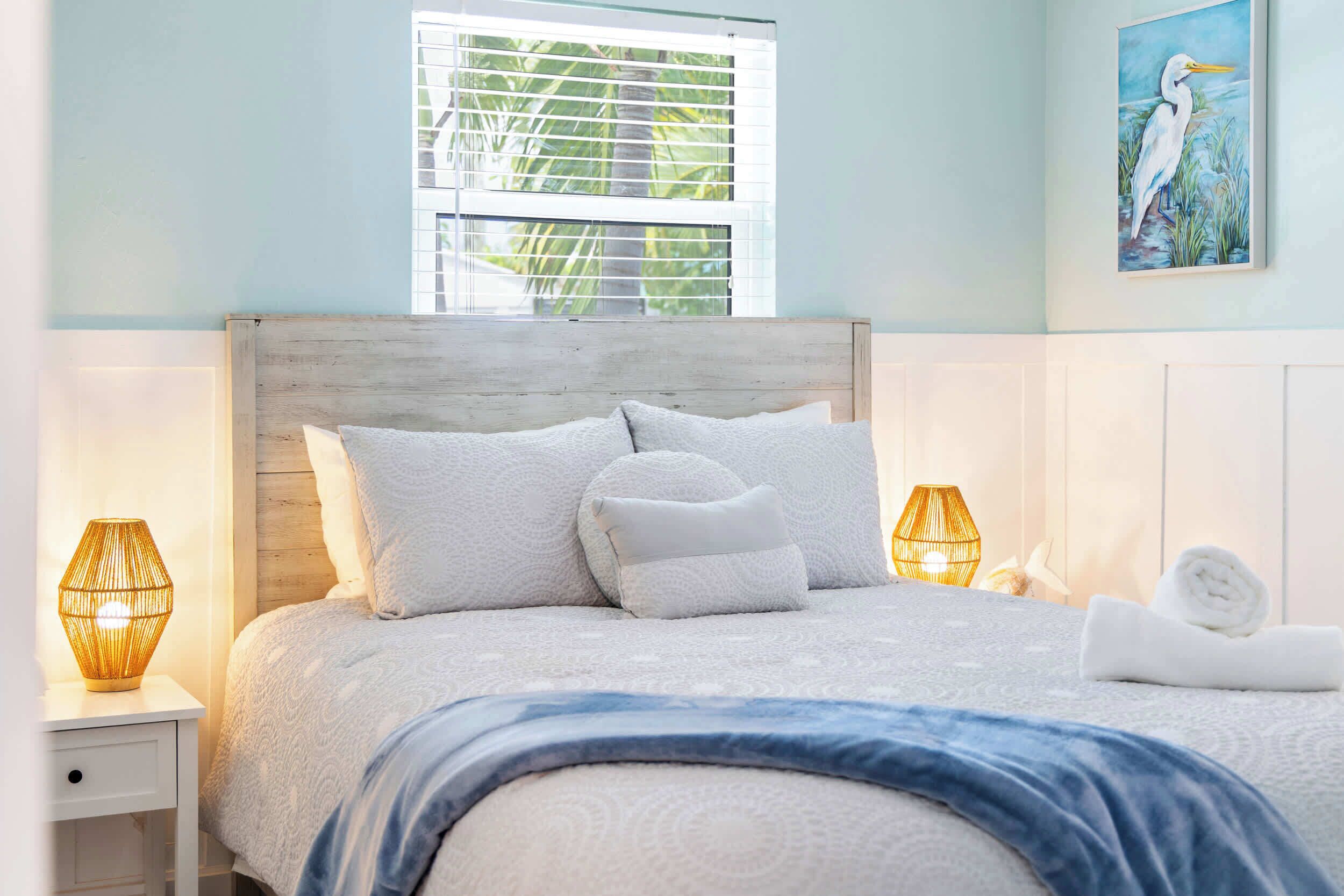 A bed with a wooden headboard, white bedding, and two bedside lamps.