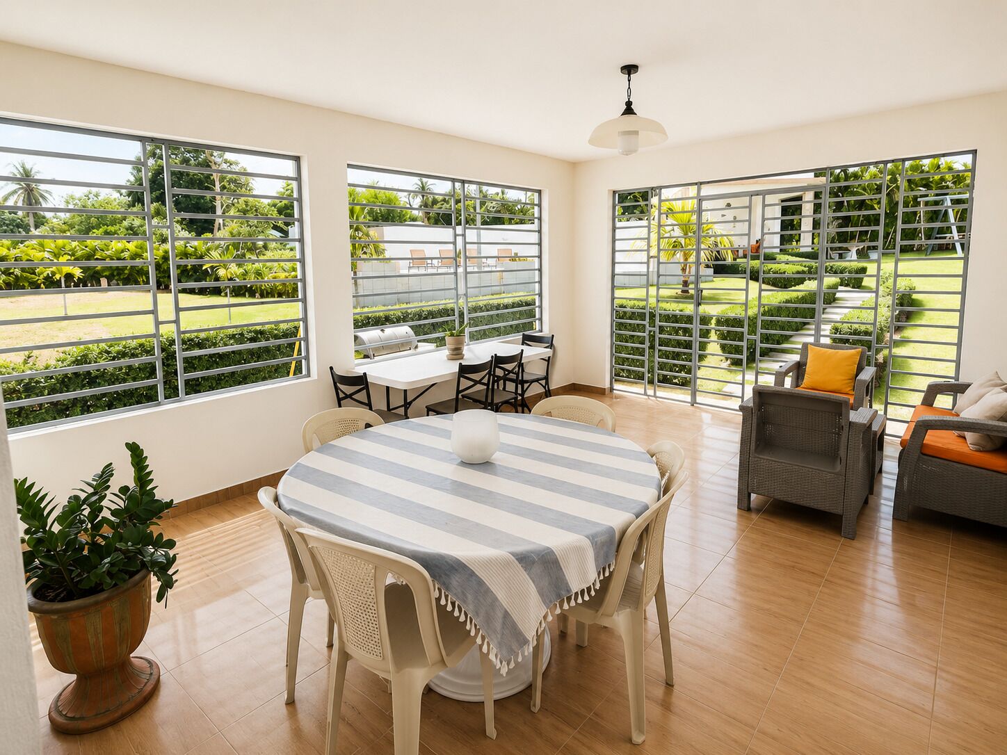 Ein Essbereich mit Tisch, Stühlen und Blick auf einen gepflegten Garten durch große Fenster.