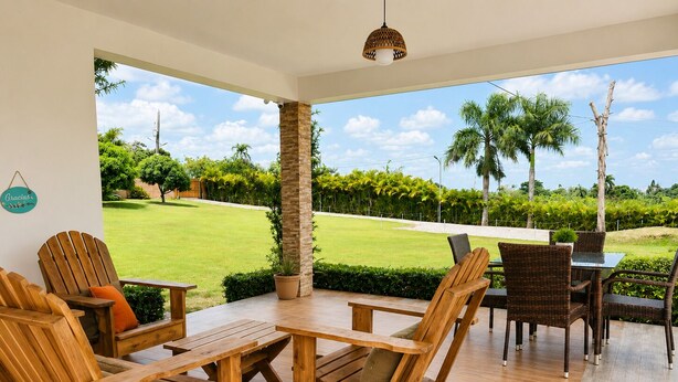 A patio with wooden furniture, a view of a well-maintained lawn, and a clear sky. - Villa la Santa, Higüey - La Altagracia (Higüey)