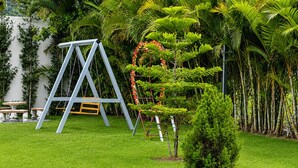 A well-maintained garden with a swing set, a small tree, and various tropical plants. - Villa la Santa, Higüey - La Altagracia (Higüey)