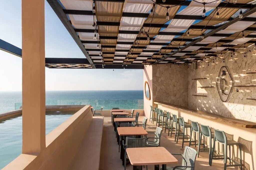 Zona exterior amb taules i cadires, una piscina i vistes a l'oceà.
