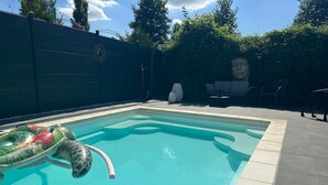 A rectangular swimming pool with a clear blue water surface, surrounded by a tiled deck. - House with a pool and tropical garden (Bruyères-sur-Oise)