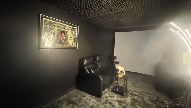 A room with a projector screen, a framed dollar bill artwork, a leather couch, and a small table with a lamp. - House with a pool and tropical garden (Bruyères-sur-Oise)