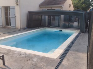 Uma piscina retangular com superfície de água azul cristalina, rodeada por um deck ladrilhado.