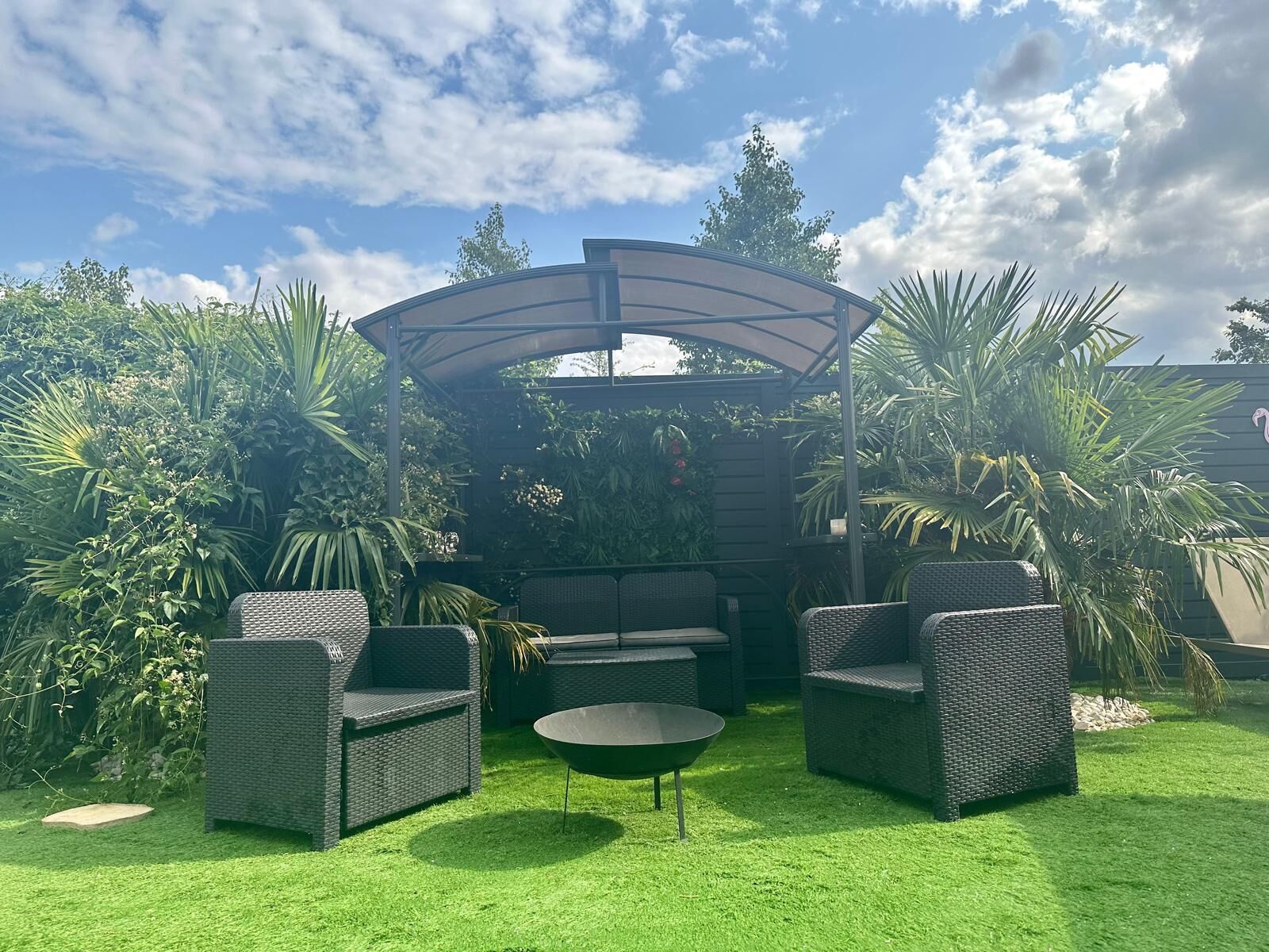 Ein Terrassenbereich mit Korbmöbeln, einem runden Tisch und einer Pergola.