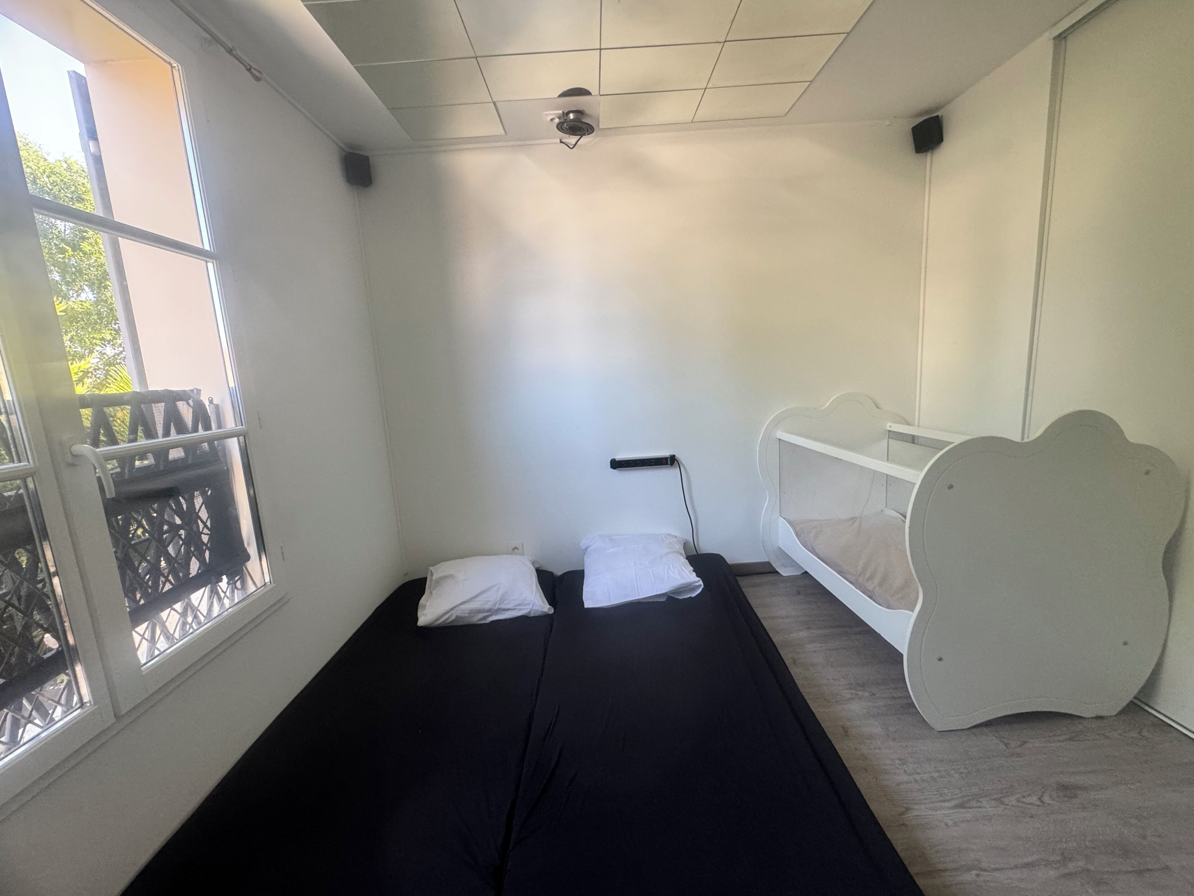 Une chambre avec un lit simple, une fenêtre donnant sur un beau paysage et un lit superposé.