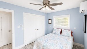 A bedroom with a bed, a ceiling fan, a window with blinds, and a door. - Beautiful spacious upgraded 2-bedroom condo sleeps 8 (St. Pete Beach)