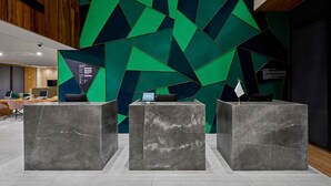 Un'area reception con tre scrivanie in marmo, un design moderno per il muro con motivi geometrici e un soffitto in legno.