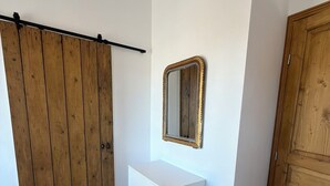 Une pièce avec une armoire en bois, une commode blanche, un miroir et une porte en bois.